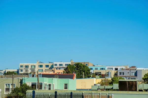 Dekoratif renklere sahip evler ve apartman dairesi ve öğlen güneşinde mavi gökyüzü arka planında fotokopi alanı. San Francisco 'nun şehir merkezindeki kentsel ya da banliyö bölgesinde..