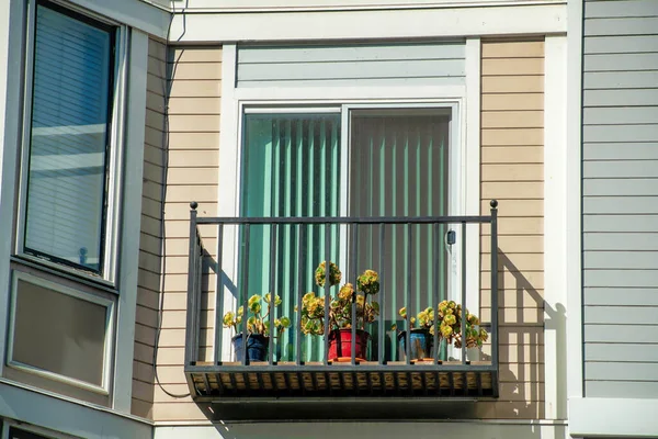 Siyah metal balkon, bej ve beyaz aksanlı ahşap balkon ya da öğleden sonra güneşinde ahşap ev ve mahallede gölge. Şehirde ya da metropolde ya da kasabada bir yerde..