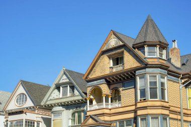 San Francisco California 'nın tarihi bölgelerinde orta sınıf bir mahallede kahverengi ve yeşil renkli evler var. Gün ortası güneşinde açık mavi gökyüzü Şehirde veya metropolde.