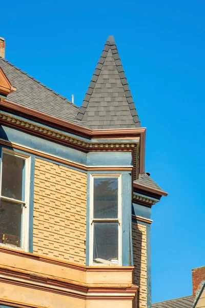 stock image Victorian style house with spire type rooftop and brown wooden slatted timber house in a downtown or suburban neighborhood. In the city in midday or late afternoon sun on residence.