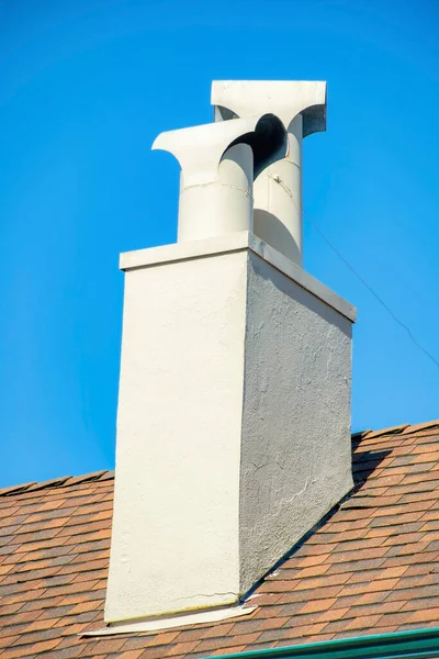 白色的粉刷烟囱通风口 喷漆的白色管道和棕色的屋顶前景明确的蓝天城市背景在中午的阳光下 在附近或房屋或结构的细节中拍摄 — 图库照片