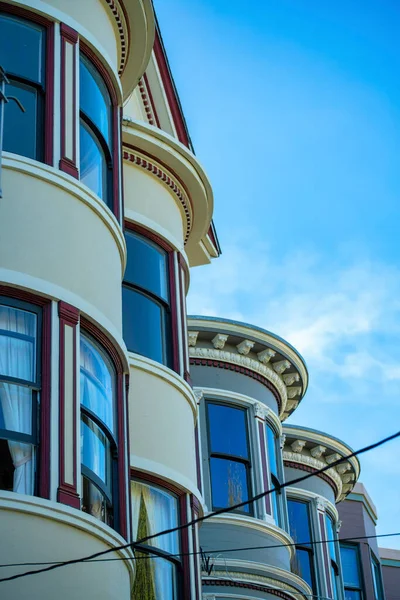 stock image Row of cylindrical or circular houses with white stucco exterior and black window accent paint with power lines and blue sky background. In the suburban city on the facade of building or apartments.