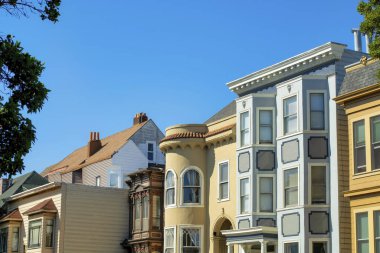 San Francisco 'nun tarihi bölgelerinde bulunan mavi turuncu ve bej dış görünüşlü modern binalar. Öğleden sonra güneşli mahallede ağaçlar görülebilir..
