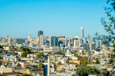 San Francisco 'nun tarihi bölgelerindeki şehir merkezine doğru öğleden sonra güneşi altında bir bakış açısı. Mahallede gökdelenleri ve mavi gökyüzü arkaplanı olan birçok bina var..