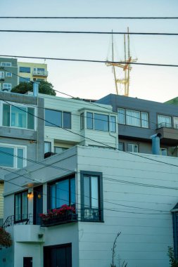 Modern apartman binaları ve arka planda sutro kulesi olan görünür elektrik hatları ve pencereleri olan birimler. Öğleden sonra geç saatlerde San Francisco 'nun tarihi bölgelerinde güneş doğar..