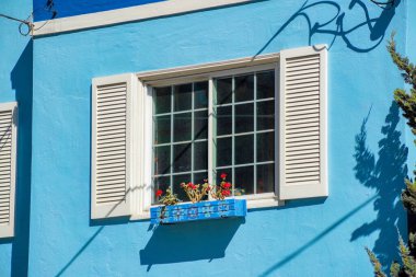 Amerika Birleşik Devletleri 'nin büyük bir şehrinde şehir merkezindeki tarihi mahallelerde ev ya da ev kenarındaki tek pencere. Mavi sıva bina cephesi ya da şehir merkezinde öğleden sonra güneş ışığı altında dış cephe.