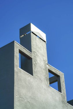 Dekoratif baca cephesi açılışlar ve metal kapaklı gri ya da mavi kaplamalı öğleden sonra güneşi altında. Kentsel ya da banliyö şehir merkezinde açık mavi gökyüzü arkaplanı.