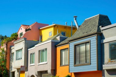 San Francisco 'nun tarihi bölgelerinde açık mavi gökyüzü ve görünür pencereleri olan modern renkli evler veya evler. Şehir merkezinde mavi turuncu bej ve beyaz bina cepheleri.
