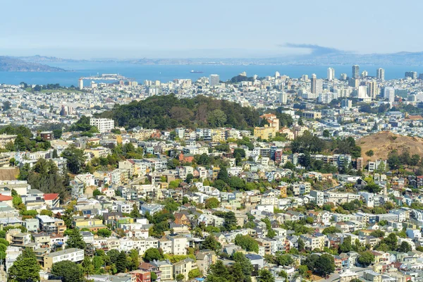 Gün ortasında ağaçlarla, yeşilliklerle ve mavi okyanuslarla kaplı yamaçlarla San Francisco California 'daki çok renkli şehir silueti.