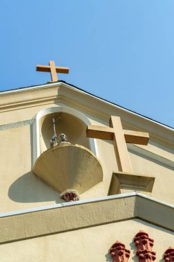 İki kilise gün ortasında binanın önünde ya da çan kulesinde turuncu sıva ve beyaz aksan renkleriyle kesişiyor. İbadet yeri süslemeleri olan mavi gökyüzü arkaplanı.