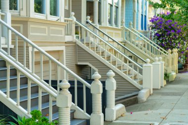 Evlerin ön bahçesinde gölgeli, modern Victoria tasarımı olan tırabzanlar ve uzakta evleri vardı. San Francisco California şehir merkezindeki şehir binaları gölgede.