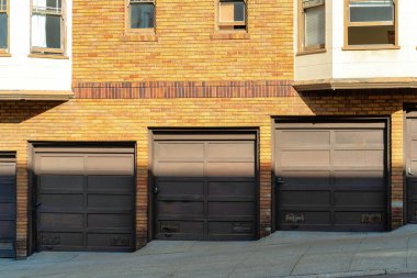 San Francisco California 'da öğleden sonra gölgesinde, tuğla binanın yanındaki kahverengi garaj kapılarında. Binanın karanlık dış cephesinde ilerleyen güneş çizgisi. Akşam saatlerinde ya da mahallede..