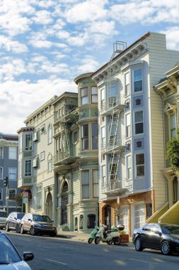 Öğleden sonra San Francisco şehir merkezinde cephesi olan modern dekoratif evler. Mavi ve bulutlu gökyüzü güneşli mahallede ya da şehirde arabalarla.