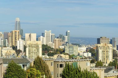 Şehir merkezindeki binalar ve akşam güneşinde ağaçlarla ve yapraklarla kaplı binalar ve dağlarla kaplı sisli mavi gökyüzü. İlkbaharın sonunda San Francisco 'da Kaliforniya' da.