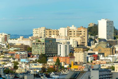 San Francisco California 'da şehrin göbeğinde birçok sıra bina ve iş yeri olan şehir merkezi güneşli. Önplanda biraz gölge, mavi ve gri gökyüzü arkaplanı.