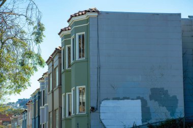 Yıpranmış ya da yaşlanmış San Francisco California şehir merkezindeki binalar ya da şehir merkezindeki evler. Öğleden sonra gölgesinde, banliyö bölgesinde ön bahçe ağaçlarıyla.