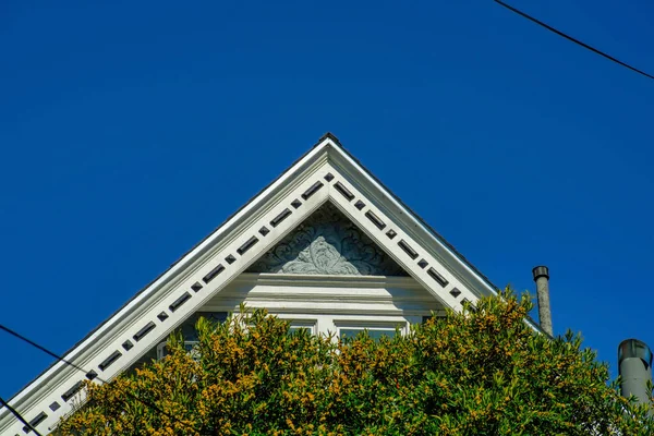 在瓷砖边缘和前院树边缘涂上带有装饰的外部和白色口音的双层树顶外墙和深蓝色天空 附近或市中心可见的电力线路 — 图库照片