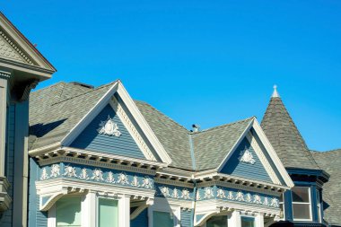 Çift gable stil çatılar ev veya ev üzerinde mavi ahşap dış ve açık çatı kiremitleri ile Victoria evi üzerinde beyaz aksan boya. Açık gökyüzünde öğleden sonra güneşinde Mahallede sıralı cephelerle.