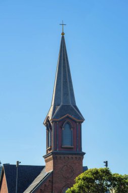 Kilise çatısı beyaz, tuğla bina dış tarafı görünür baca boruları ve şehir merkezinde gece yarısı gölgesinde çaprazlama. Dini merkezlerde açık mavi ve beyaz gökyüzü.