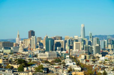 Gökdelen sırasına sahip şehir manzarası. Tepe ve eğimli mavi ve beyaz gökyüzü arkaplanı görünür binalar ve pencereler. San Francisco 'da öğleden sonra güneşinde.