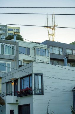 Modern apartman binaları ve arka planda sutro kulesi olan görünür elektrik hatları ve pencereleri olan birimler. Öğleden sonra geç saatlerde San Francisco 'nun tarihi bölgelerinde güneş doğar..
