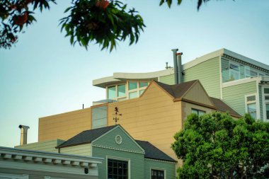 San Francisco California 'nın tarihi semtlerinde üst üste renkli ve dekoratif ev çatıları. Şehir merkezinde. Gece geç saatlerde banliyölerde gölgede kalan ön bahçe ağaçları..