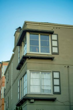 Modern, koyu pencereli sıva bina ve beyaz eğimli mavi gökyüzünde tuğla bina arka planına sahip düz çatı. San Francisco California 'nın tarihi bölgelerinde günün ilerleyen saatlerinde....