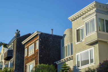 San Francisco 'nun tarihi bölgelerinde sıva ve ahşap kaplamalarla dekoratif ev cepheleri. Akşamüstü güneşiyle banliyölerde mavi gökyüzü.