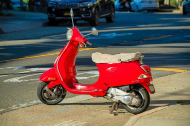 Amerika 'nın şehir merkezindeki semtlere öğleden sonra güneş ışığında yiyecek ve paket teslimatı için kırmızı scooter. Bej koltuklu kırmızı gövde ve görünür farlı siyah lastikler..