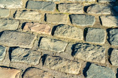 Cobblestone or brick facade on pathway for travel or transportation with multicolor stones on exterior. Texture for detail or design on the surface with grout between cracks in urban area.