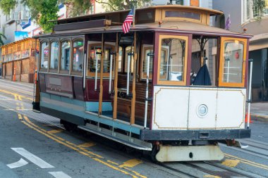 Cable car in the historic districts in san francisco california deep in the heart of city with white color and wooden accents. In early morning shade on streets and road for transport of passengers.