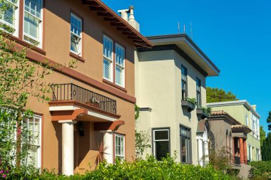 Row of brown beige and green house exteriors or facades in downtown neighborhood in suburban area of city. In the historic districts of san francisco california in middle class american dream town.