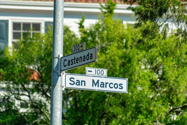 Whit and black road sign in the historic districts of san francisco california that says san marcos street and castenada. Bright sun with suburban house and front yard trees background in city.