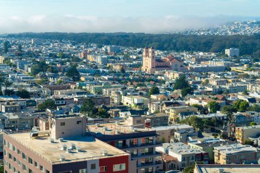 Bustling city with a great many buildings houses and businesses in midday sun with moutains and foggy clouds. Late in afternoon in the historic districts of downtown San Francisco California.