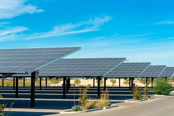 Solar pannels in rows in a parking lot or car park used as covering in the sweltering sun in Arizona. Clear blue sky with some clouds in a business or industrial area or in an apartment complex.