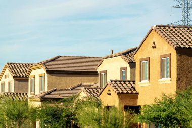 Row of suburban houses in middle class modern suburban neighborhood with double gable style rooftops. In late afternoon sun with visible trees and windows in american dream city.