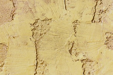 Beige or yellow stucco and cement exterior of building or house or home in late afternoon sun light with texture ridges. Used for design purposes as a pattern to fill in detail on other objects.