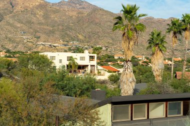 Modern mansions in the hills of the sonora desert in the moutains of arizona with visible palm trees and cactuses. Houses or homes in rural neighborhood in the wilderness of southwestern america.
