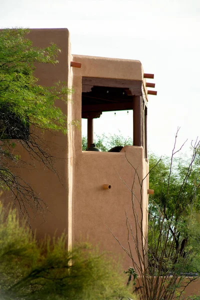 Adobe style building with flat roof and balcony with rain gutter posts and block style design in back yard in neighborhood. In wilderness area of the rural community in arizona desert town.