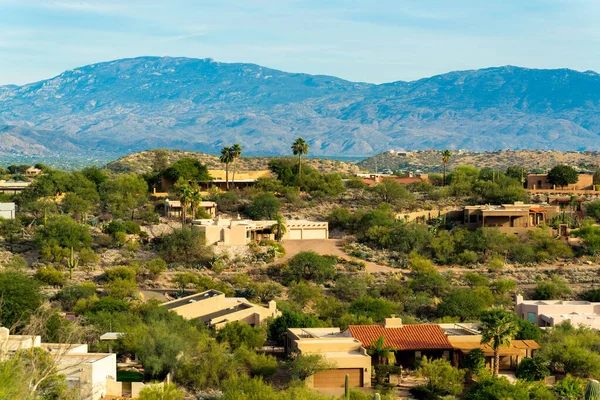Rolling hills of arizona in the wilderness and rural areas of suburban mansion community in southwestern united states. Visible cactuses with background shady moutains and clear blue sky.