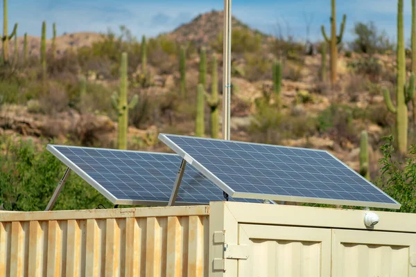 Dual solar or photovoltaic pannel in the desert sunlight in arizona gathering natural energy from the skies. On shipping container with cactus and natural landscape hill background in wilderness.
