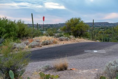 Helicopter landing pad of cement or asphalt ground with gravel with airport wind sock orange in distance. Used in national park for search and rescue or for fire department and crews with vehicles.