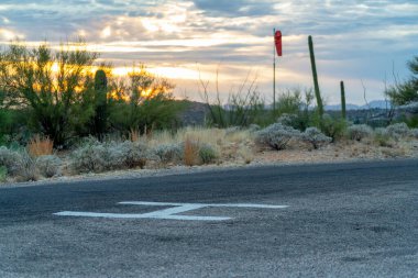 Helicopter landing pad with giant H letter with white paint on cement and gravel for helicopters and saftey and rescue crew. In a national park for disaster relief crews to land vehicles in wilderness.