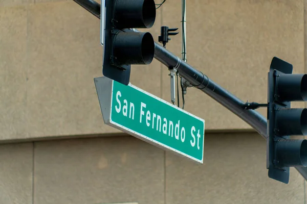 Sign on street light that say san fernando street in silicon valley san jose in downtown city with black traffic lights. In afternoon shade in heart of the urban area in office business districts.