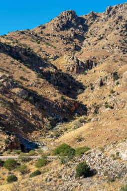 Natural cliffs on the edge of mountain peaks with small transportation road for cars and vehicles in sunlight. In the great outdoors of arizona in wild western united states midday.