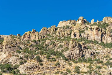 Rock face and stone formation on side of sunlit mountain in late afternoon sun in the great outdoors desert in arizona. Clear blue sky in the wild west southwestern united states in hills.