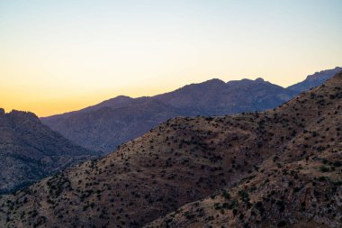 Rolling mountain hills in the cliffs and ridges of tuscon arizona in late afternoon sunset or early sunrise sun with orange haze sky. Natural vegetation in sonora desert with summits and precipice.