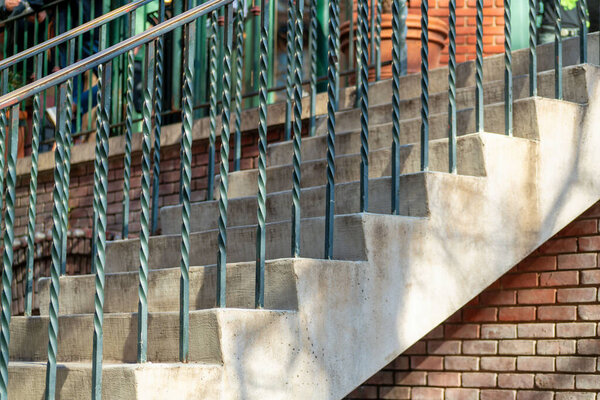 Metal spiral decorative hand rails black with cement stairs and brick facade in late afternoon downtown city architecture. In the neighborhood or urban part of town suburban background.