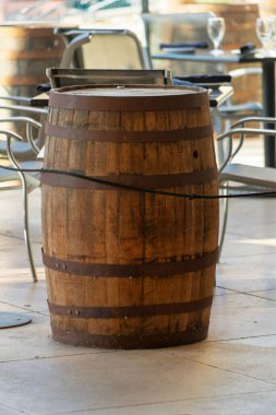 Decorative barrel used for table to corral customers in certain area for dining in restaurant in commercial business shopping districts. In shade place of business with tables and chairs nearby.