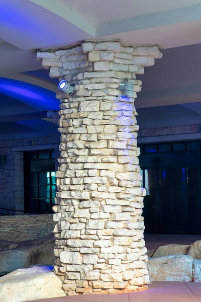 Stone and rock pillars with blue lighting in industrial area or in mall and shopping center in commercial business districts. Late afternoon sun with shadow near storefronts and shops in neighborhood.